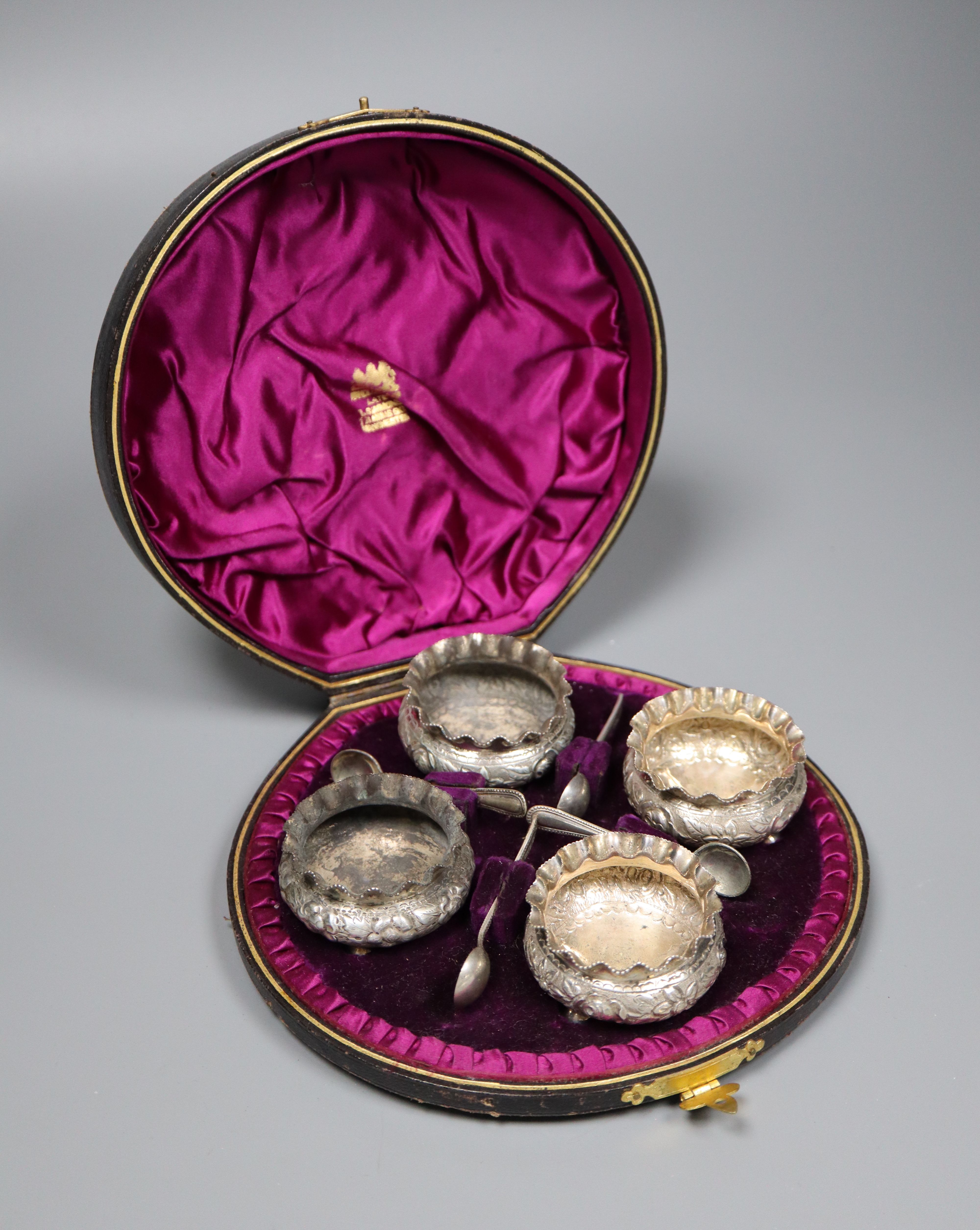 A cased set of four Victorian silver circular salts, Birmingham, 1886 and four spoons.
